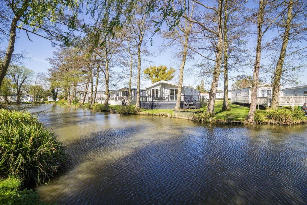 a river with houses and trees in the background at Stunning Lodge Boasting Lake Views At Weely Bridge Holiday Park Ref 69005l in Weeley