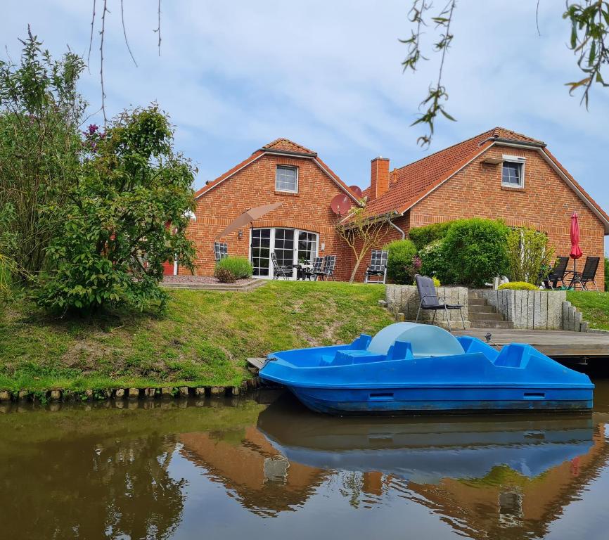 un barco azul sentado en el agua frente a una casa en Waterkieker, en Greetsiel