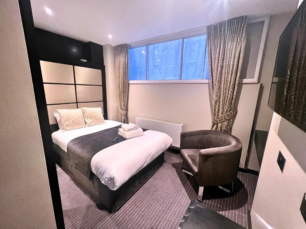 a bedroom with a bed and a chair and a window at Great St Helen Hotel in London
