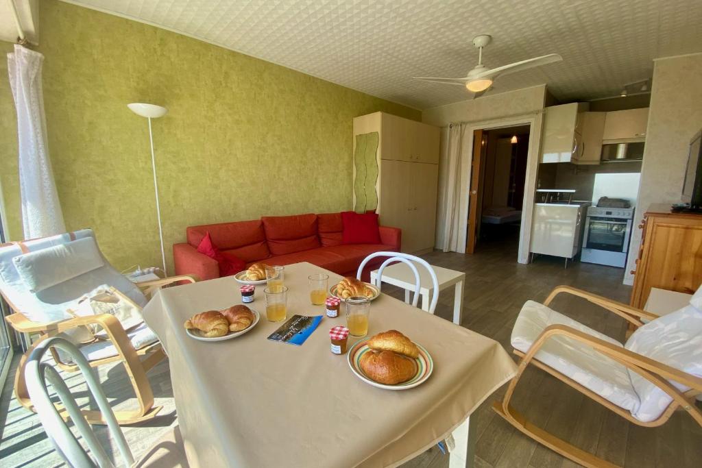 - un salon avec une table et des assiettes de nourriture dans l'établissement LES AIGRETTES - Studio proche de la plage, au Grau-du-Roi