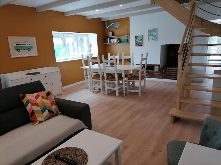 ein Wohnzimmer mit einem Sofa, einem Tisch und Stühlen in der Unterkunft Maison centre bourg, 6 pers, 5 minutes de la plage in Plomeur