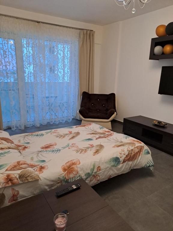 a bedroom with a bed and a chair and a window at Happy Rental Apartments 1 in Craiova