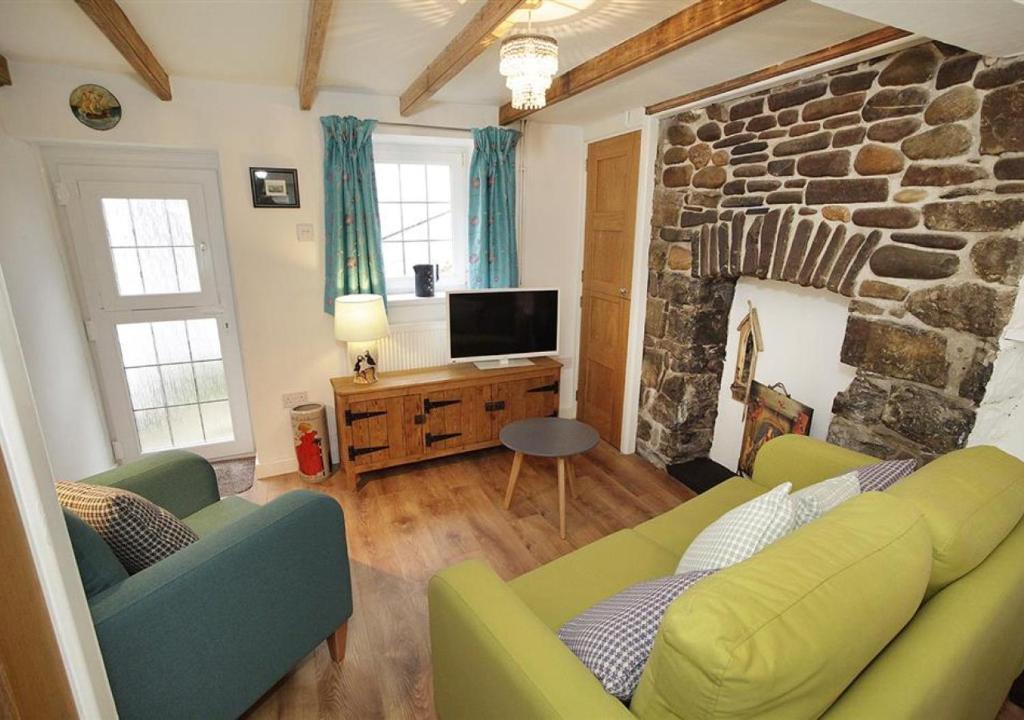 a living room with a couch and a stone fireplace at Bwthyn Bach in The Mumbles