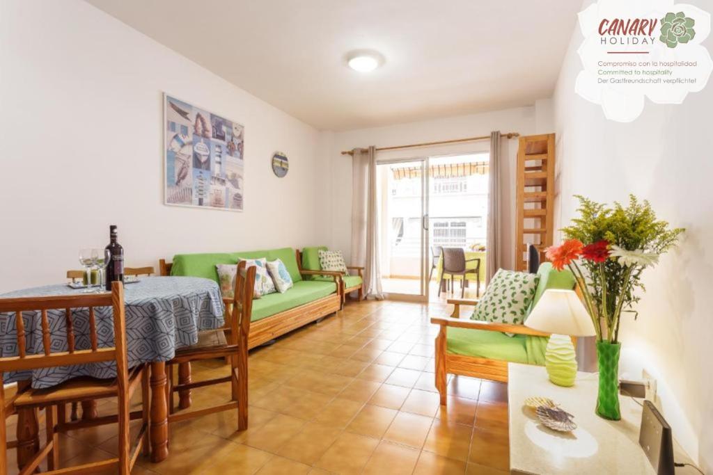 Una sala de estar con un sofá verde y una mesa. en Vivienda Vacacional El Faro, en Puerto Naos, en Los Llanos de Aridane