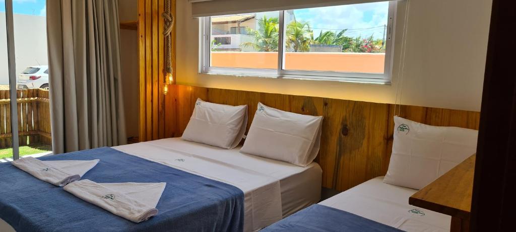 two beds in a room with a window at Casa Gostoso Mar in São Miguel do Gostoso