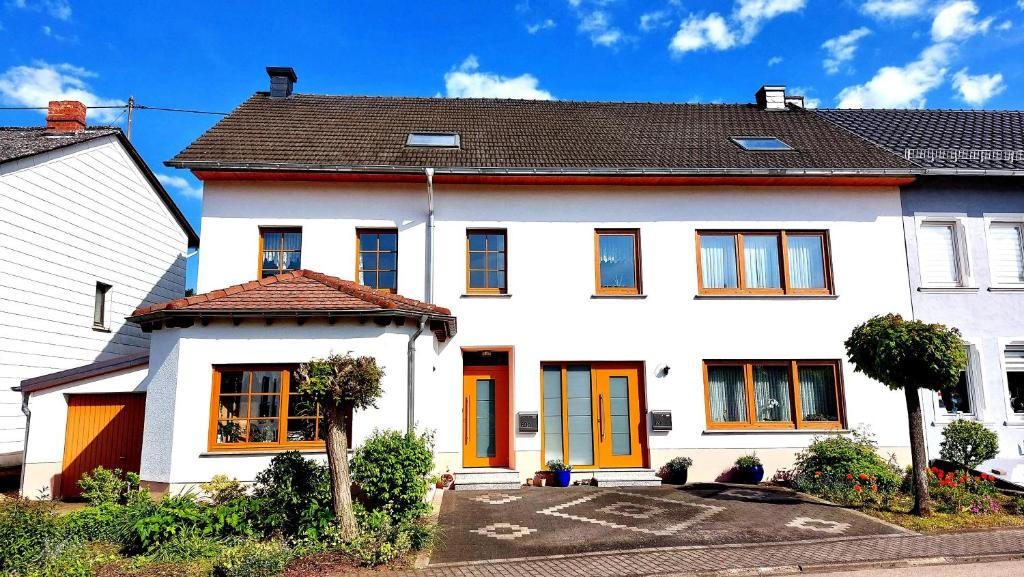 Biały dom z pomarańczowymi drzwiami na ulicy w obiekcie Ferienhaus Fisch 