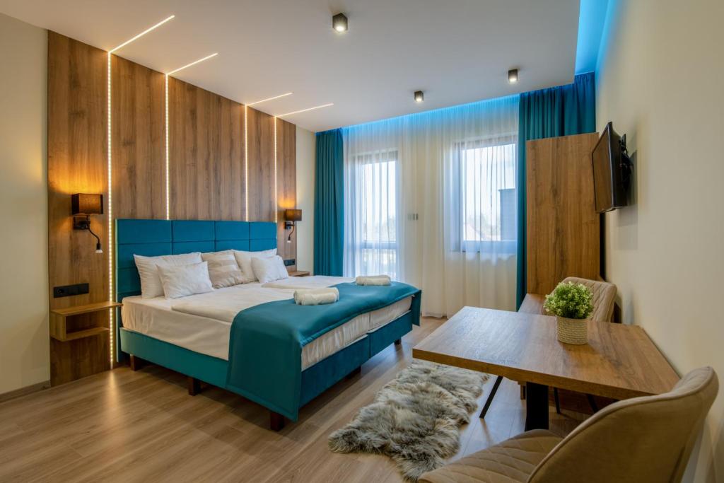 een slaapkamer met een blauw bed en een tafel bij Várkonyi Apartman in Gyula