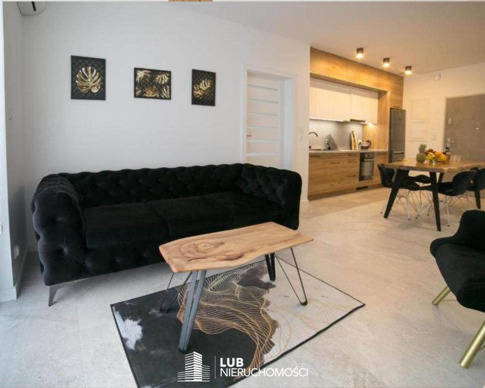 een woonkamer met een zwarte bank en een tafel bij Oxygen apartament nr 2 in Mielec