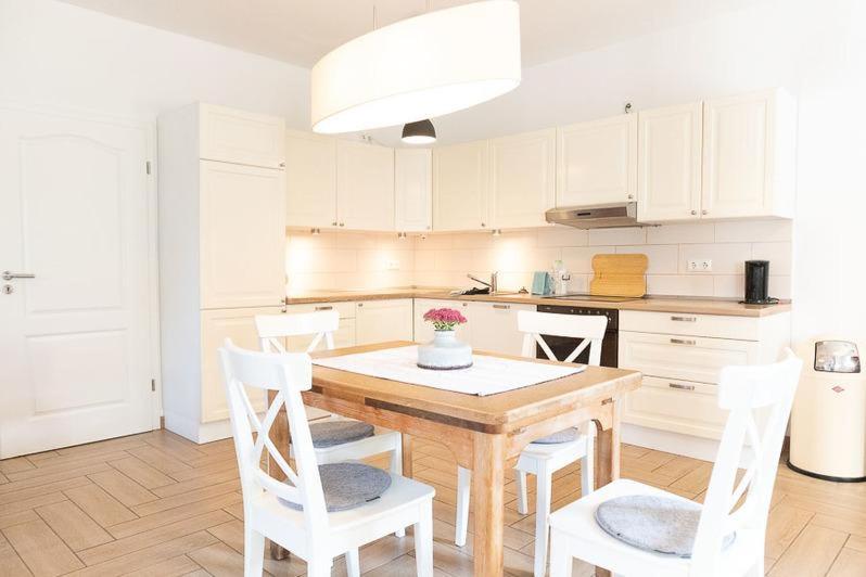 cocina con mesa de madera y armarios blancos en Ahrentschildt's Ferienwohnung im Reetdachhaus, 