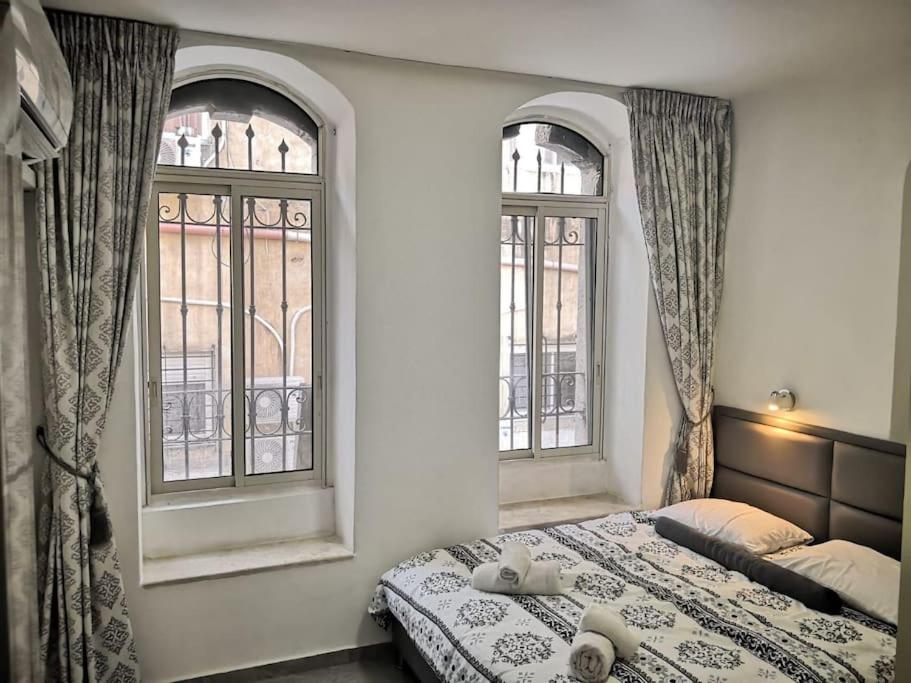 a bedroom with two windows and a bed with towels at Beautiful apartment in the center ofJerusalem 4 in Jerusalem