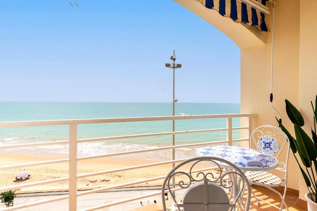 a balcony with a table and chairs and the beach at Genteel Home Victoria in Cádiz