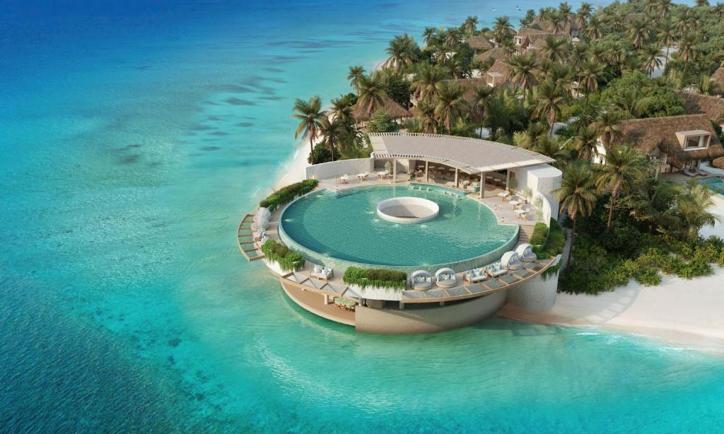 an island with a swimming pool in the ocean at Six Senses Kanuhura in Lhaviyani Atoll