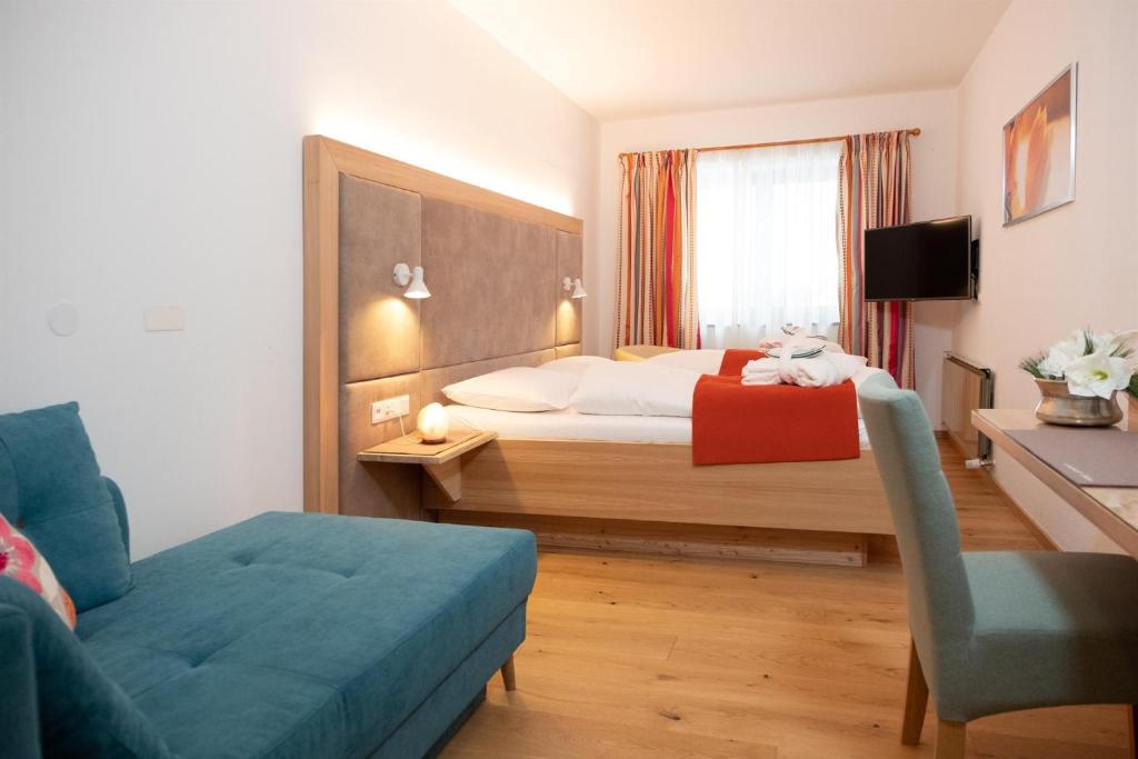 オイゲンドルフにあるSantner, Hotelのベッド、ソファ、椅子が備わるホテルルームです。