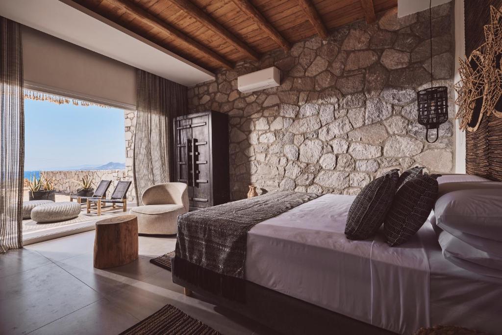 a bedroom with a bed and a stone wall at Serenity Suite Milos in Mandrakia