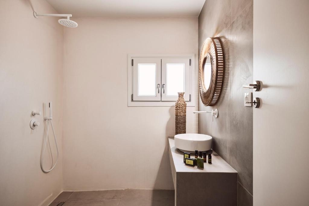 bagno bianco con lavandino e specchio di Serenity Suite Milos a Mandrakia