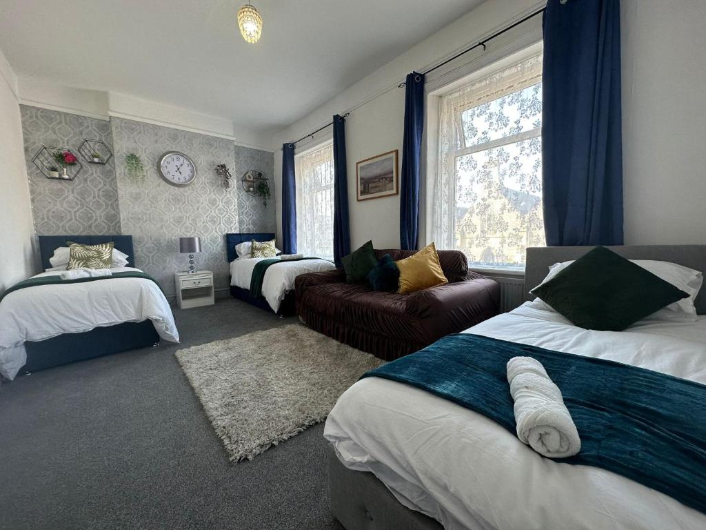 a bedroom with two beds and a couch and a window at 4 Bed House! 10%OFF! Groups, Contractors! 9 Guests - Garden - Free On street Parking in Cardiff