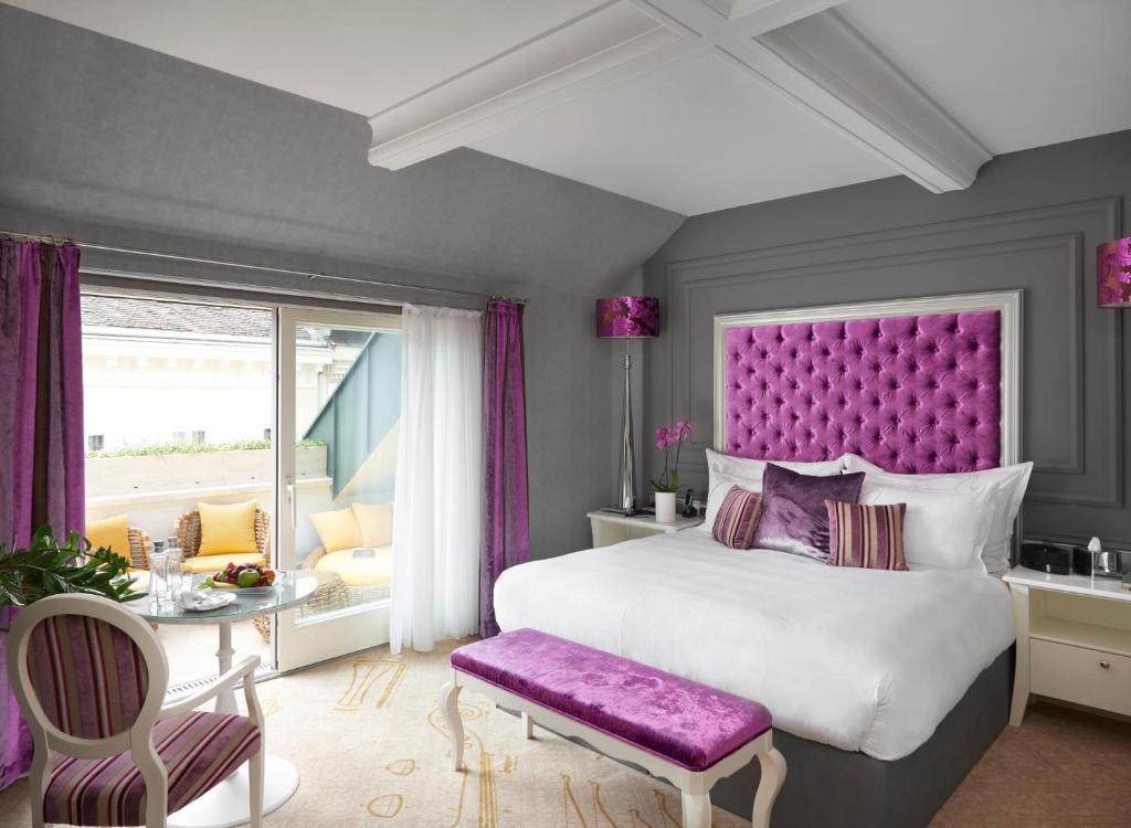 Schlafzimmer mit einem großen Bett mit einem lila Kopfteil in der Unterkunft Aria Hotel Budapest by Library Hotel Collection in Budapest