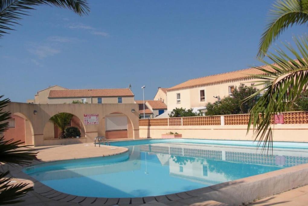 una gran piscina en un patio con un edificio en Mon Appart à la plage, piscine, wifi, tv + Netflix, en Frontignan