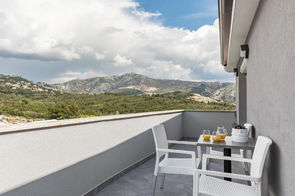 een balkon met een tafel en stoelen en bergen bij Apartments Villa Salona Sky in Solin