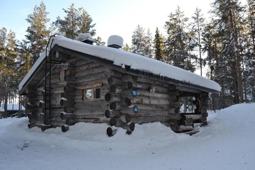 una cabaña de madera con nieve encima en Ferienhaus in Kemijärvi mit Offenem Kamin, en Vuostimo