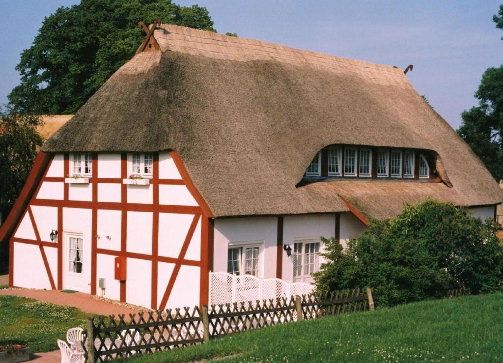 a house with a thatched roof and a fence at Ferienwohnung in Wohlenberg mit Terrasse, Grill und Garten in Klütz