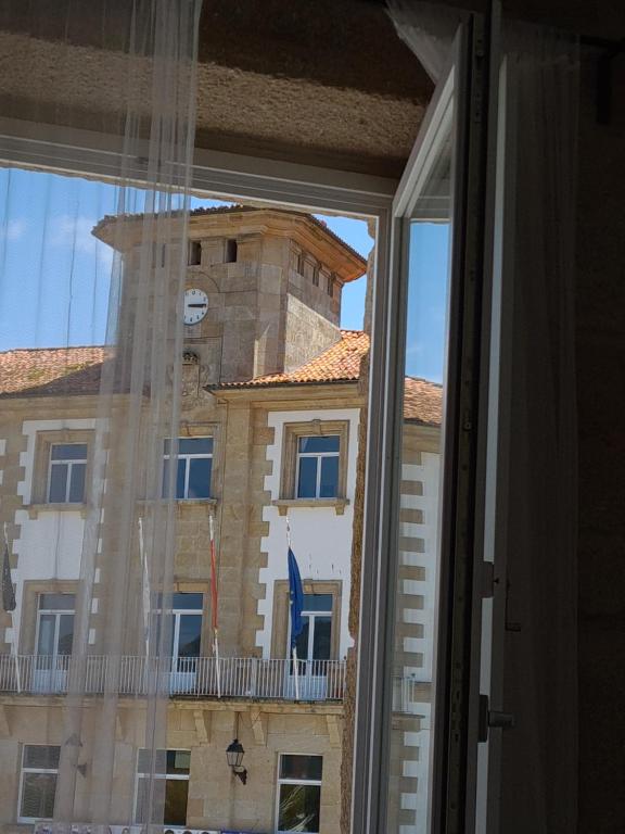une fenêtre donnant sur un bâtiment avec une tour d'horloge dans l'établissement Hospedaje CasaSampedro, à Muros