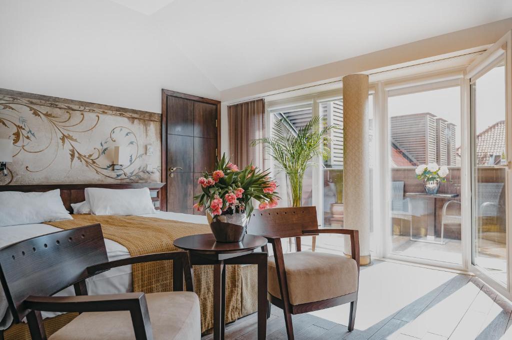 a bedroom with a bed and a table with flowers on it at Mamaison Le Regina Boutique Hotel in Warsaw