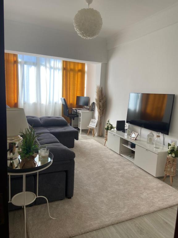 sala de estar con sofá azul y TV de pantalla plana en An elegant & cozy apartment en Amadora
