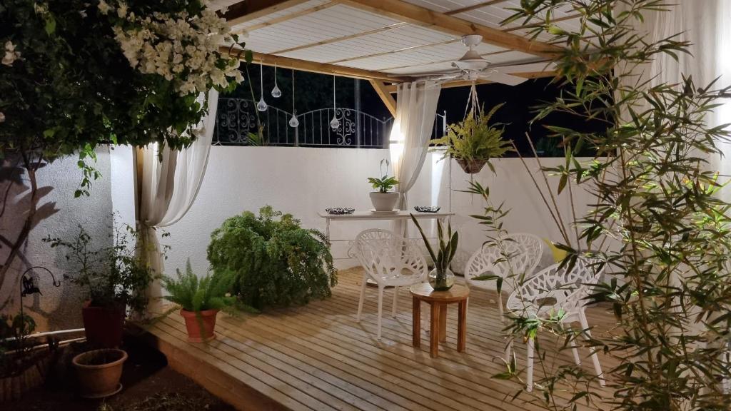 a patio with white chairs and potted plants at Your perfect getaway ... in Palmyre