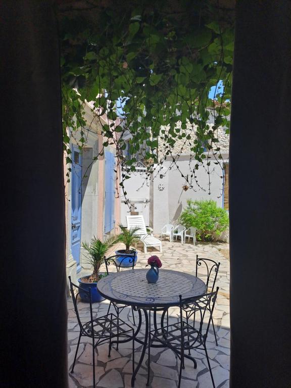une table avec des chaises et un vase au-dessus dans l'établissement La maisonnette avec SPA, PISCINE et CLIMATISATION, à Sainte-Vallière