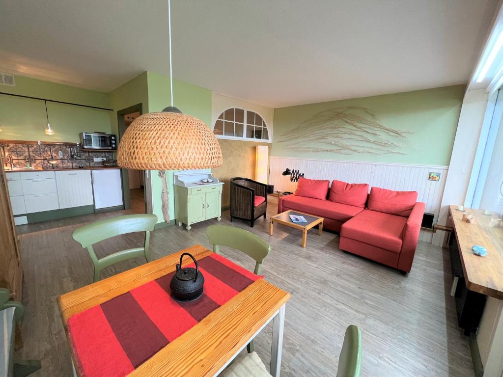 ein Wohnzimmer mit einem roten Sofa und einem Tisch in der Unterkunft Ferienpark Sierksdorf App 555 - Strandlage in Sierksdorf