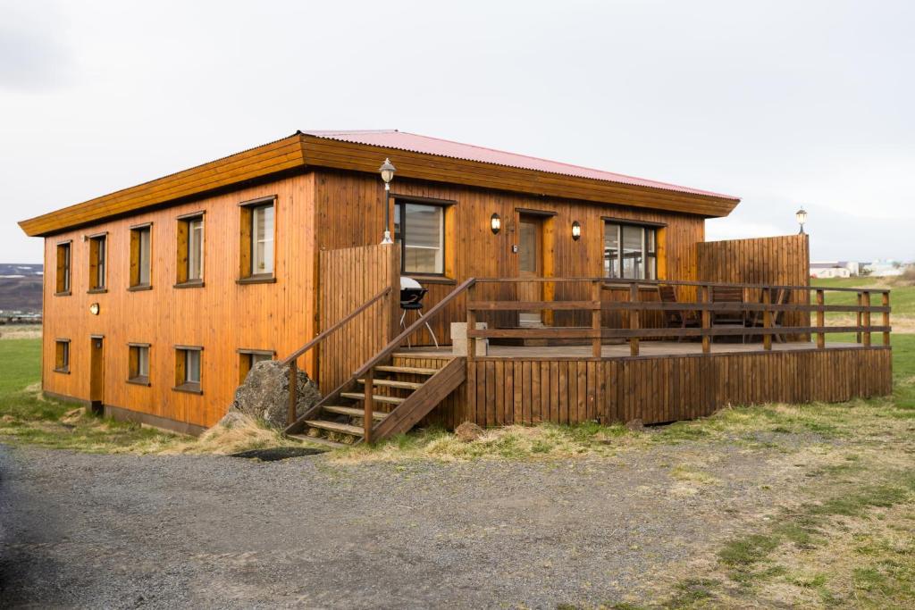 a wooden house with a staircase in a field at Guesthouse Helluland in Þingeyjarsveit