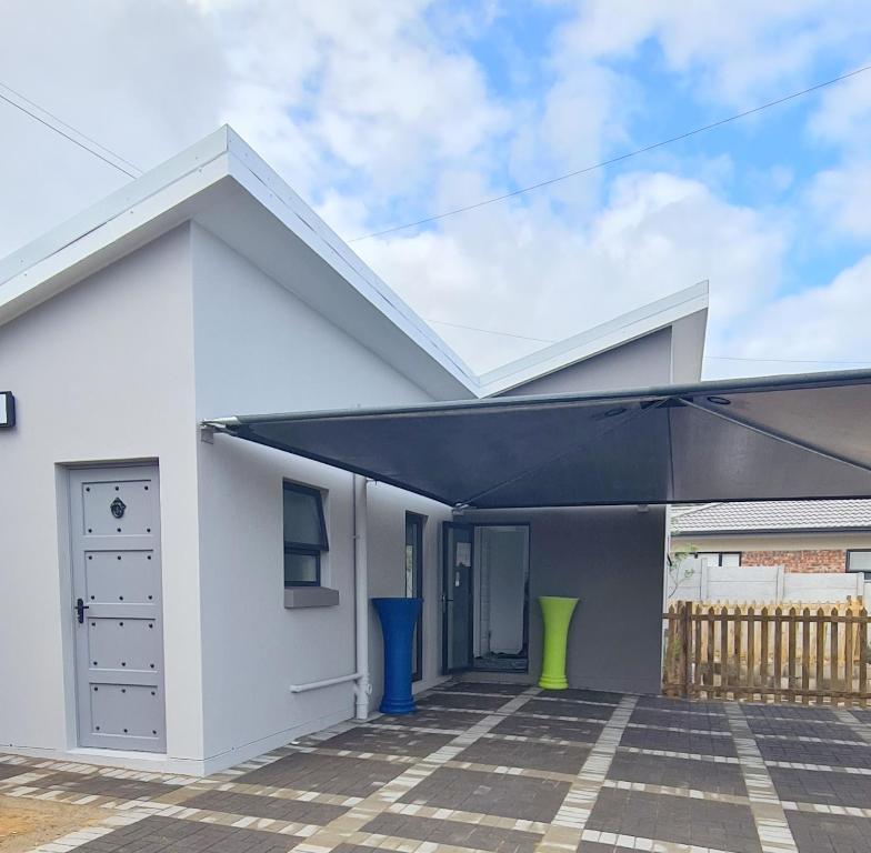 a white house with a black awning at Villa Dubaai 5 in Mossel Bay