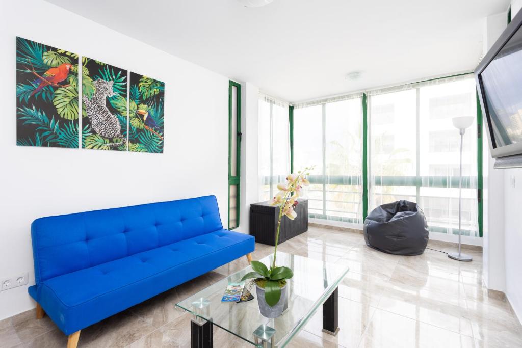 een woonkamer met een blauwe bank en een glazen tafel bij Tre spaziosi appartamenti a 150m dal lungomare di Las Americas in Arona