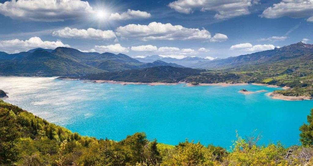 a view of a blue lake with mountains in the background at La Palatriere in Le Sauze-du-lac