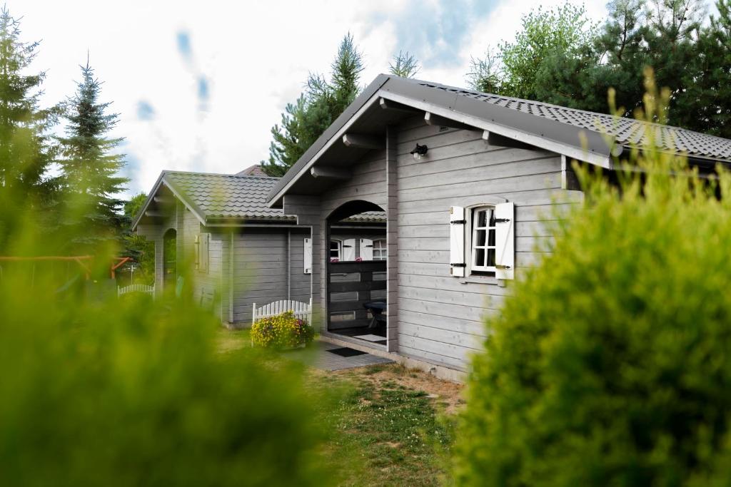 een klein grijs gebouw met een deur in een tuin bij domki szenodo na Jodłowej in Debina