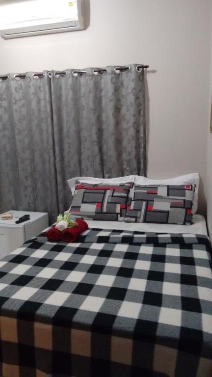 a bed with a black and white checkered blanket at Lima hospedagem caseira in Olímpia
