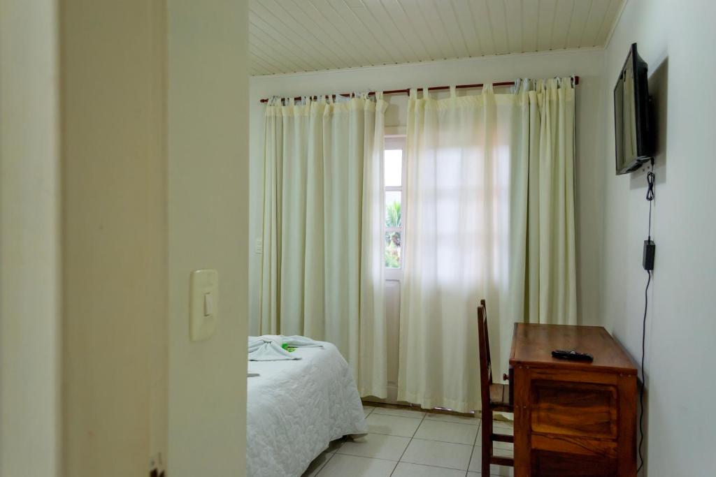 a bedroom with a bed and a window and a desk at Pousada Estrada do Ouro in Angra dos Reis