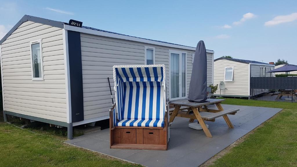 einen blauen und weißen Stuhl, einen Regenschirm und einen Tisch in der Unterkunft Campingland Ostsee - Mobilheim 157Sandburg in Schashagen