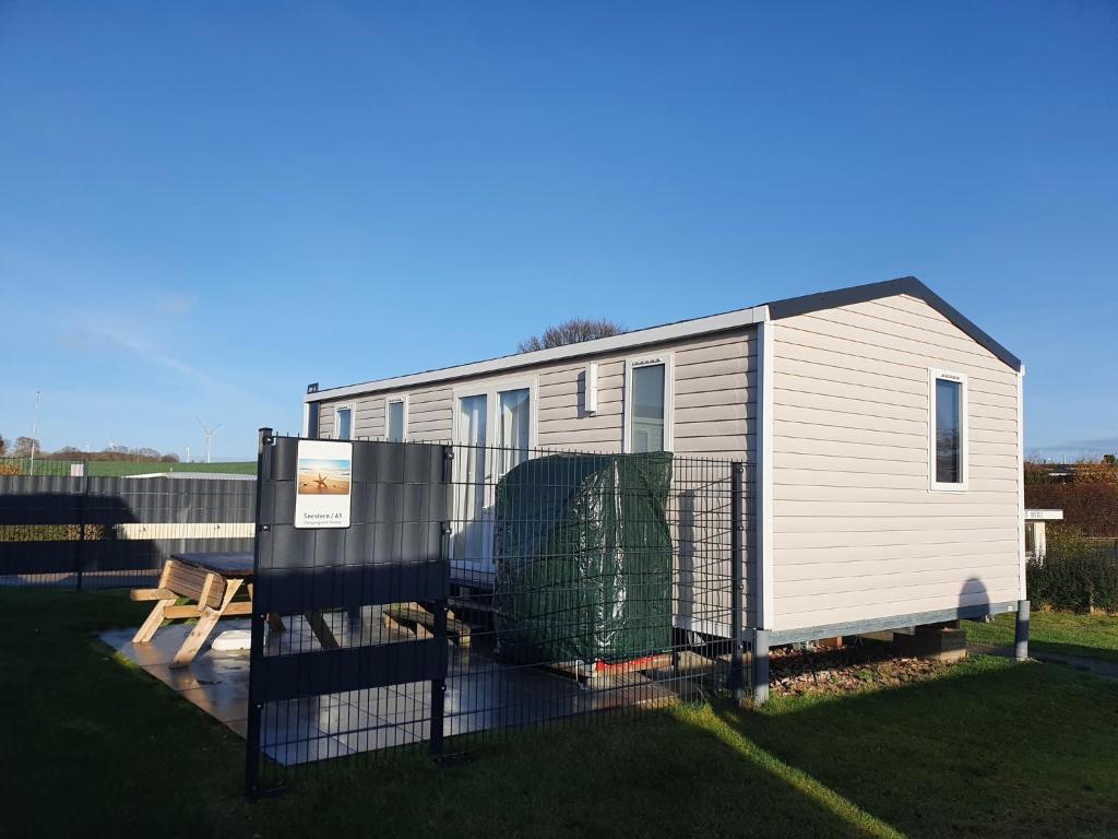 a mobile home with a fence and a bench at Campingland Ostsee - Mobilheim A1Seestern in Schashagen