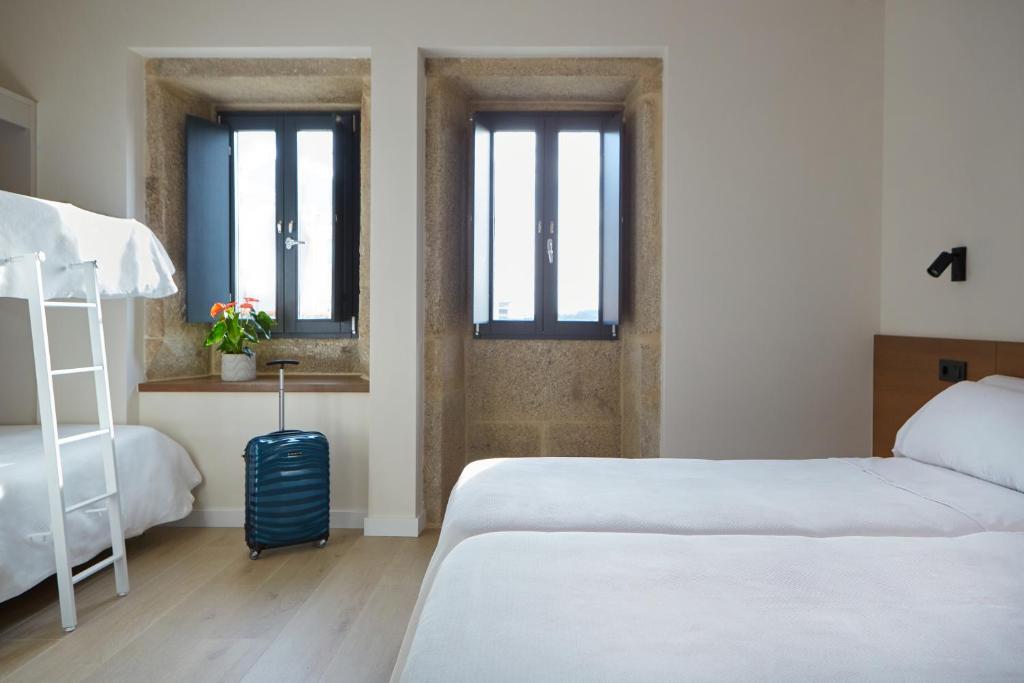 sypialnia z 2 łóżkami i walizką w obiekcie Hotel Trina 20 w mieście Palas de Rei 