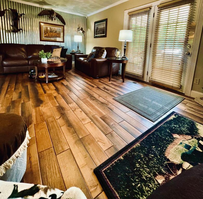 a living room with a leather couch and wooden floors at Browning Lambert Resort - Hatfield McCoy and Local Off-Road Trails in Rock