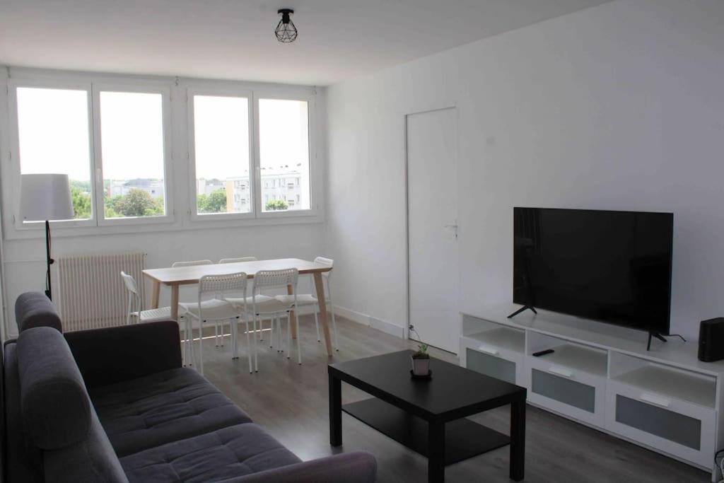 - un salon avec un canapé, une télévision et une table dans l'établissement Appartement au pied du métro., à Toulouse