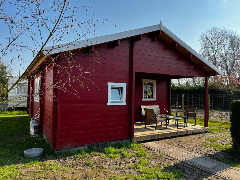 a red shed with a table and chairs on a deck at Lodge on the campsite in Oostvoorne