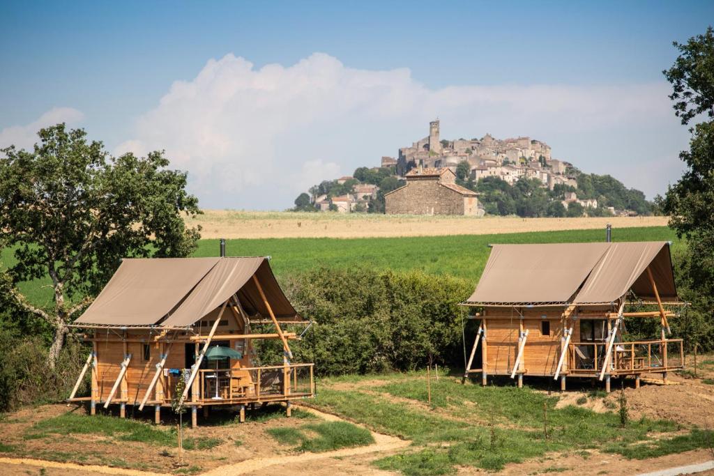 dos casas en un campo con un castillo en el fondo en Huttopia Pays de Cordes sur Ciel, en Albi