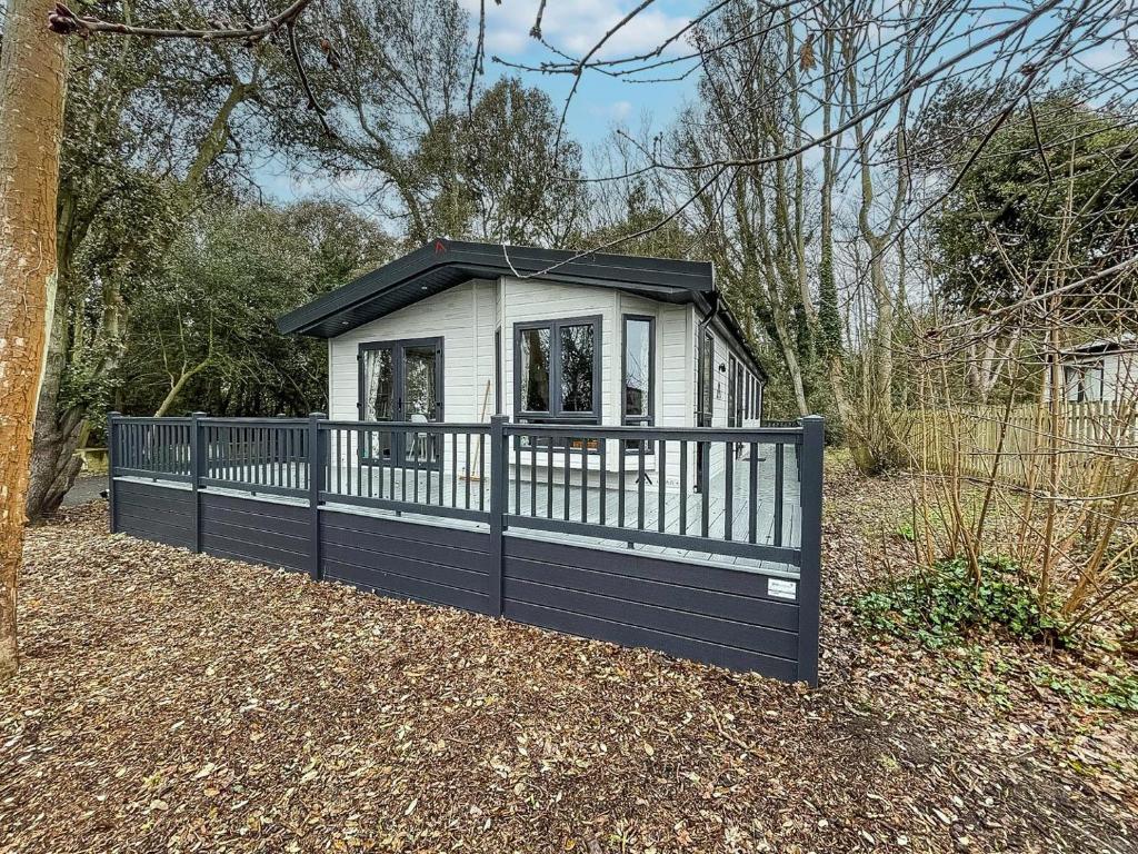 una pequeña casa con una valla en blanco y negro en Beautiful Lodge With Decking At Azure Seas In Suffolk, Sleeps 6 Ref 32217og en Lowestoft