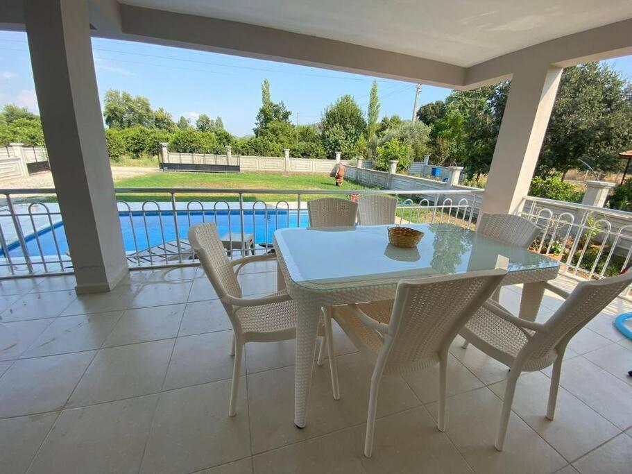 una mesa y sillas en un patio con piscina en Doğanın kalbinde havuzlu villa, en Koycegiz