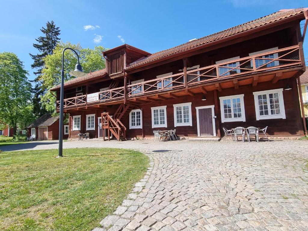ein großes Holzgebäude mit einer Terrasse davor in der Unterkunft Vandrarhemmet Färgaren in Eksjö