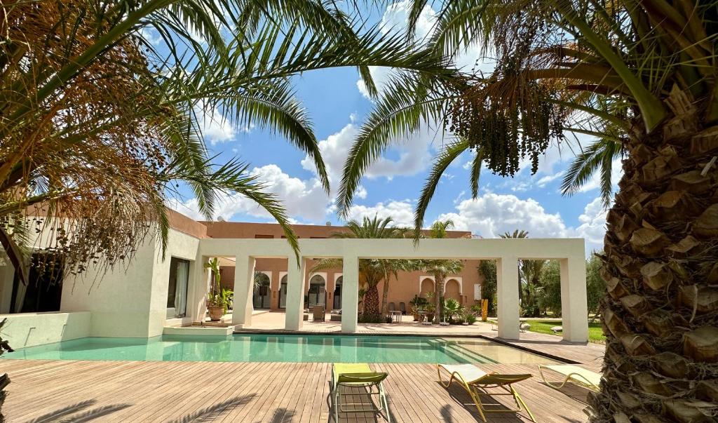 a villa with a swimming pool and palm trees at Les Jardins de Kesali in Marrakesh
