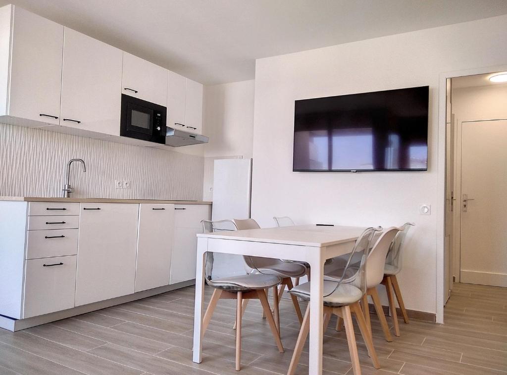 - une cuisine blanche avec une table et des chaises blanches dans l'établissement Résidence Graziella Appartement 510, à Juan-les-Pins